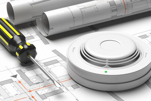 Fire safety system construction. Smoke detector on blueprint drawing background. Fire protection,  emergency evacuation plan . 3d illustration